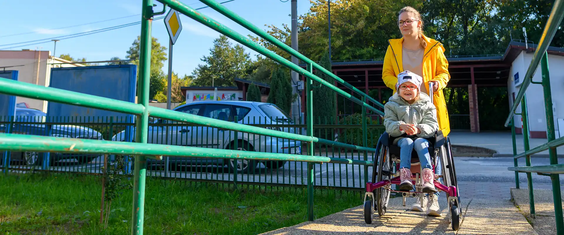 Happy girl in accessibility device being pushed by caregiver