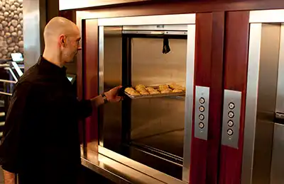Waiter using Matot dumbwaiter to transport food