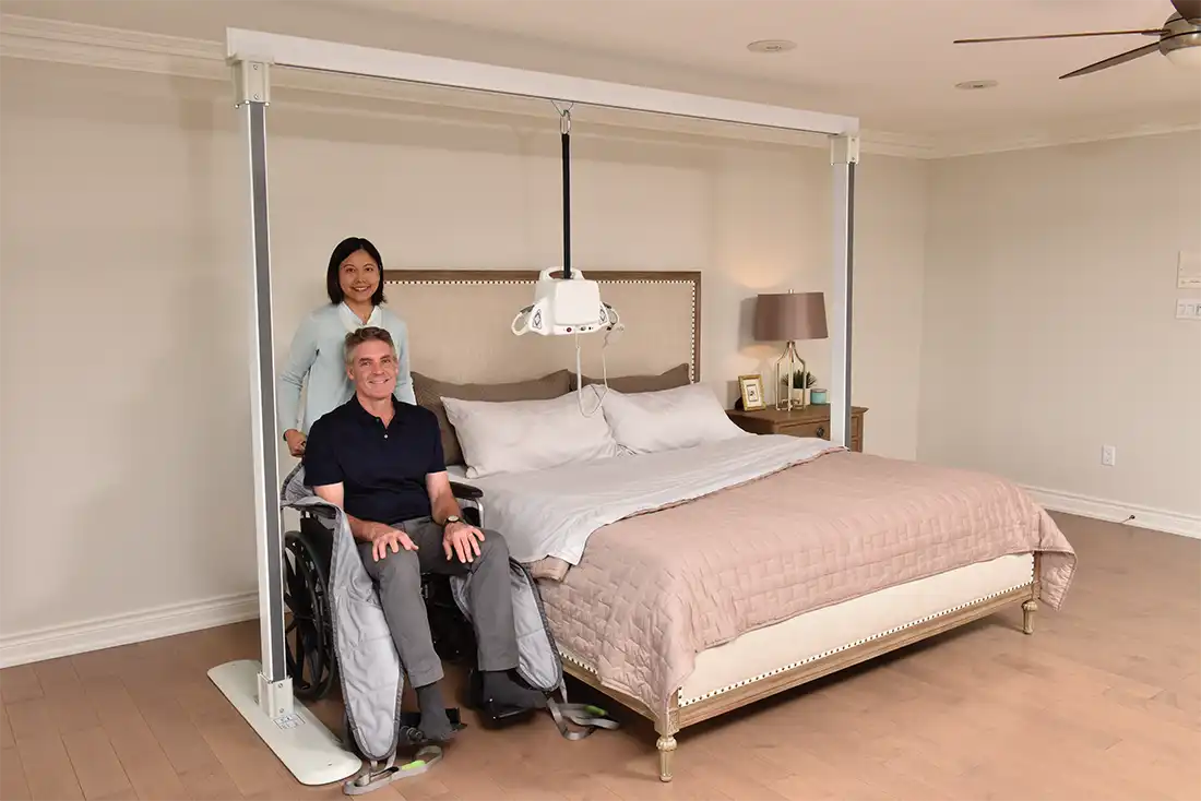 caregiver with patient underneath ceiling lift in bedroom
